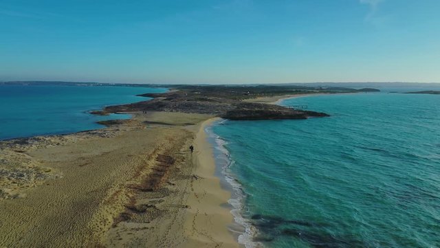 Aerial video of the Illetas beach, on the island of Formentera, with a person walking, at sunset time.