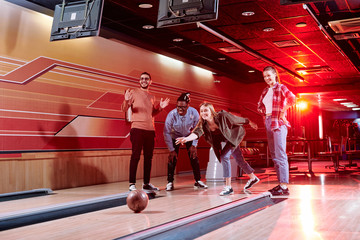 Group of young cheerful friends of various ethnicities standing by bowling alley