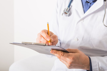 Doctor  with stethoscope writing RX prescription on clipboard on white background, closeup. Medical service
