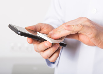  Doctor disinfecting cleaning mobile phone screen preventive wiping for SARS-CoV-2 . COVID-19 Pandemic Coronavirus.