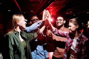 Group of young cheerful intercultural friends giving each other high five