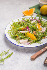 Fresh green organic  salad with arugula, orange slices, chicken, nuts on white  plate, top view. Healthy eating, dieting concept