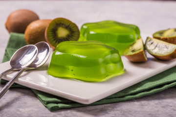 Delicious fresh two green jelly with kiwi slices on concrete table