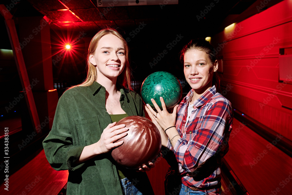 Sticker Two pretty cheerful female players with bowling balls looking at you before game