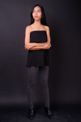 Full body shot of young beautiful Asian woman thinking with arms crossed