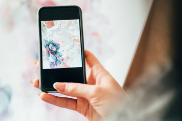 Fototapeta na wymiar Contemporary art. Virtual gallery. Hands of woman taking picture of abstract floral watercolor painting