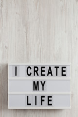 'I create my life' words on a modern board on a white wooden background, top view. Overhead, from above, flat lay. Copy space.
