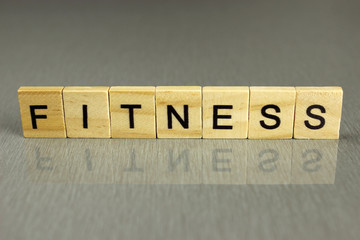 word fitness is made of square wooden letters on a gray background