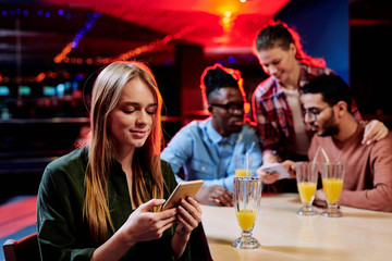 Pretty young blond female looking through photos or posts in social networks