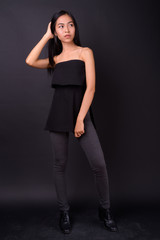 Full body shot of young beautiful Asian woman thinking