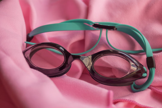 Close-up of black diving goggles on a pink microfiber towel with natural lighting