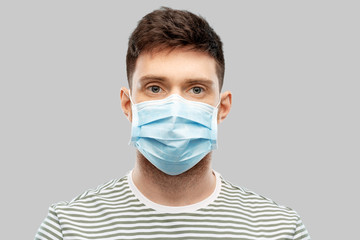 health protection, safety and pandemic concept - young man in protective medical mask over grey background