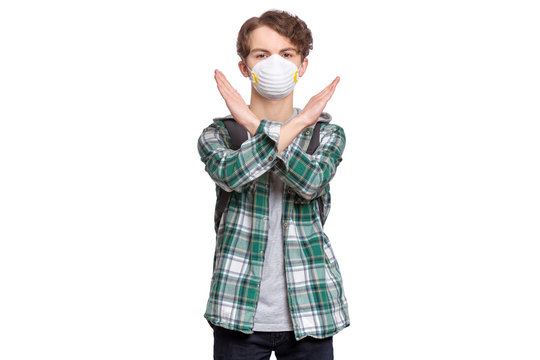 Concept of coronavirus quarantine. Child wearing medical protective mask during flu virus, making stop gesture. COVID-19. Student teen Boy doing stop sign with crossed hands, isolated on white.