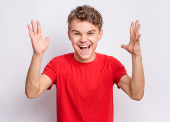 Happy teen boy screaming, on grey background. Funny child looking at camera and shocked. Emotional...