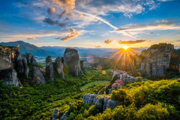 Sunset over monastery of Rousanou and Monastery of St. Nicholas Anapavsa in famous greek tourist destination Meteora in Greece on sunset with sun rays and lens flare - obrazy, fototapety, plakaty