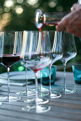 Man pouring red wine into glasses.