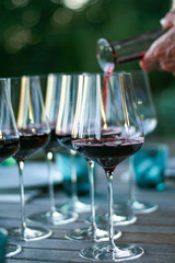 Man pouring red wine into glasses.