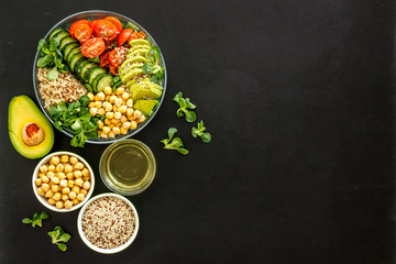 Vegan bowl. Avocado, quinoa, tomato, spinach and chickpeas vegetables salad on black table top-down copy space