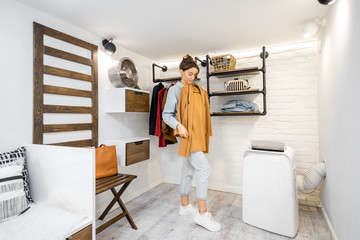 Young woman trying a jacket, choosing clothes to wear in the modern small wardrobe at home