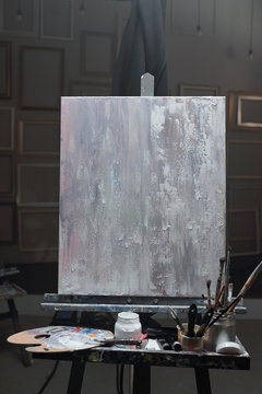 Easel with unfinished picture and set of stuff for professional painting