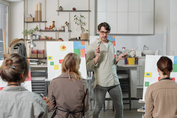 Young confident teacher of painting course standing in front of audience