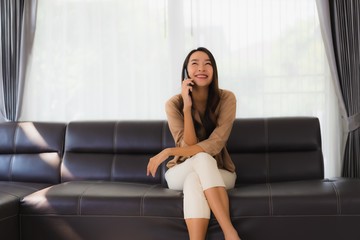 Fototapeta na wymiar Portrait beautiful young asian woman use mobile smartphone or cellphone with coffee cup on sofa living room