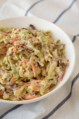 Homemade Creamy Broccoli Slaw in a white bowl on cloth, low angle view. Close-up.