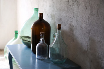 Composizione di contenitori vintage (vecchie damigiane in vetro e altri contenitori per vino o...