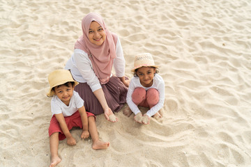 Asian kids having leisure time with their mother at the beach.