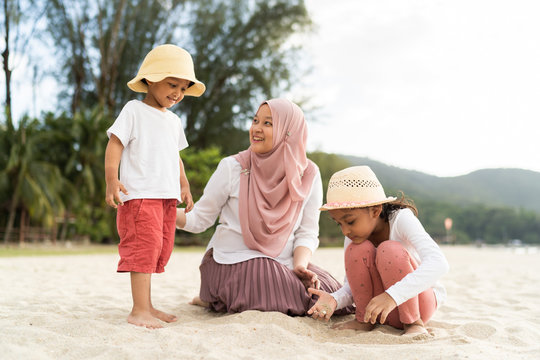 Asian kids having leisure time with their mother at the beach.