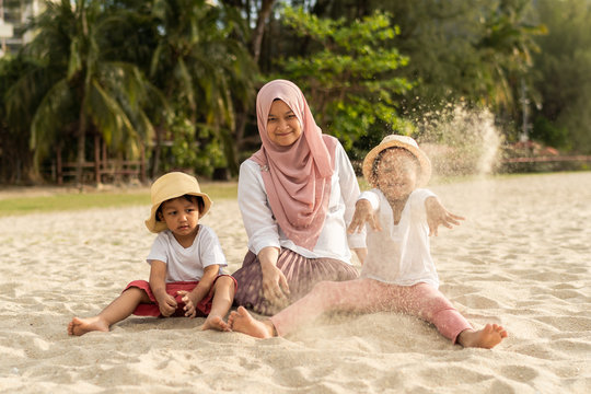 Asian kids having leisure time with their mother at the beach.