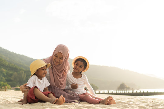 Asian kids having leisure time with their mother at the beach.
