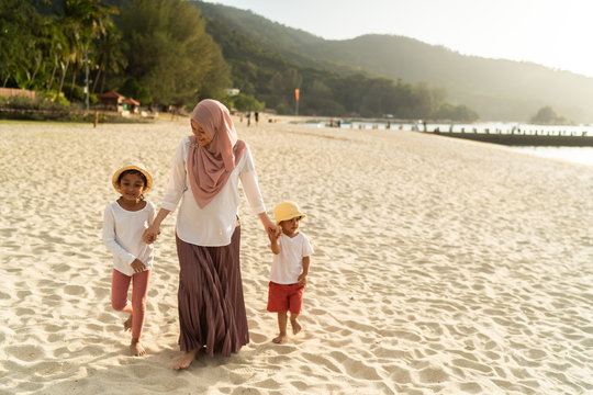Asian kids having leisure time with their mother at the beach.