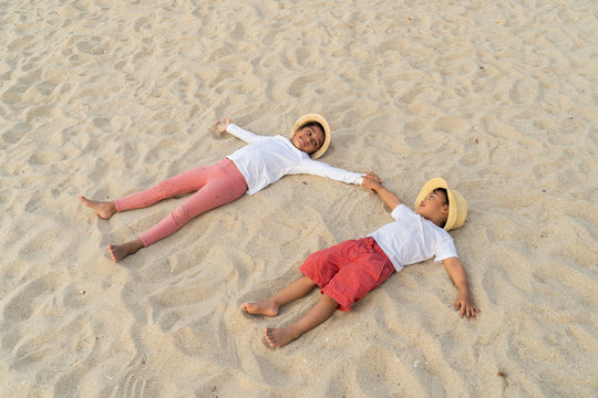 Kids lying down happily together on a beach sand