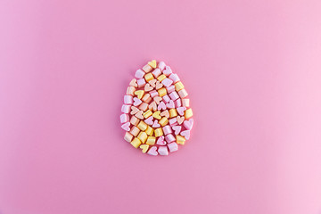 Single multicolored easter egg made of small marshmallows hearts on a pink background. Concept.