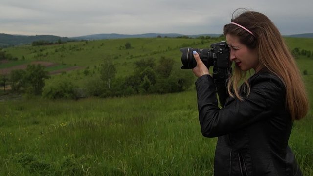 Girl taking pictures in mountainous terrain. Nature around. Camera moves backwards