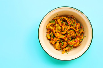 Chicken with yellow curry paste on blue background. Copy space
