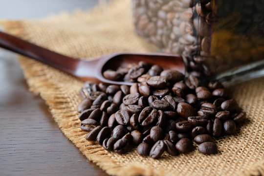 深入りコーヒー豆とガラス瓶。roasted coffee beans with a glass jar on a old wooden table