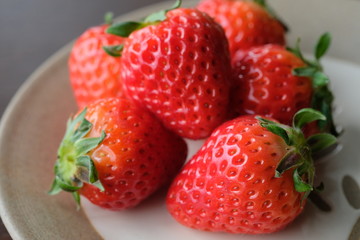 お皿の上の新鮮いちご。Fresh strawberries with leaf on a old wooden table