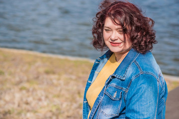 Mature plus size woman, American or European appearance walks in the city enjoying life. Lady with excess weight, stylishly dressed at the city park .Natural beauty