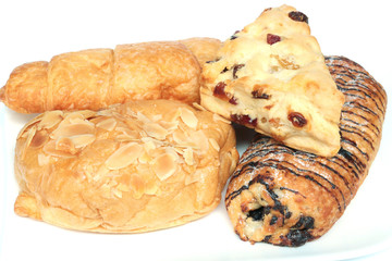 The bakeries (croissant, croissant with chocolate, croissant with almond, cranberry scone) isolated on white background. Close-up photography.