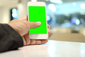 Mobile smart phone with blank green screen on hands of man. Selective focus and shallow of field.