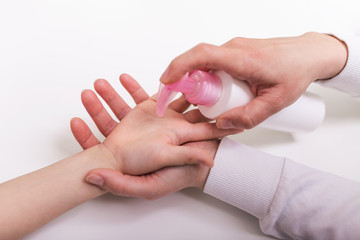 Mother applying cleaning gel on kids hand, applying alcohol gel to make cleaning and clear germ, bacteria, Health care concept, coronavirus pandemic. COVID-19. stay at home