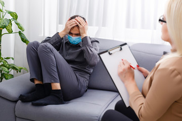 Psychologist woman and male coronavirus patient over gray cabinet