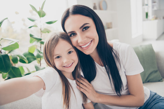 Closeup photo of cute small girl and young attractive mom hugging making selfies for online blog harmony homey mood spend free time together home house indoors