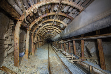 Fototapeta na wymiar Underground gold mine tunnel with steel arch and rails