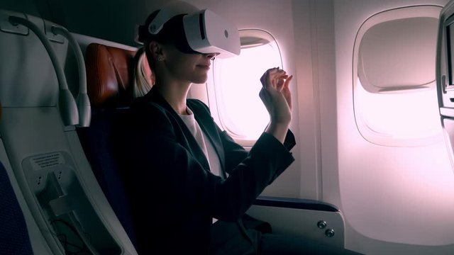 Successful corporate director in electronic goggles working in cyberspace using high technology for testing 3d dimension and immersion, woman in VR headset drawing sketch during business air trip