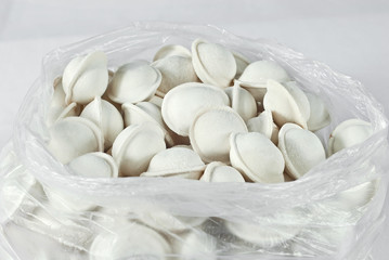 Frozen homemade dumplings in a package. Many dumplings on a white background.