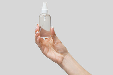 Female hands using hand sanitizer spray dispenser over light grey background