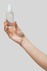 Female hands using hand sanitizer spray dispenser over light grey background